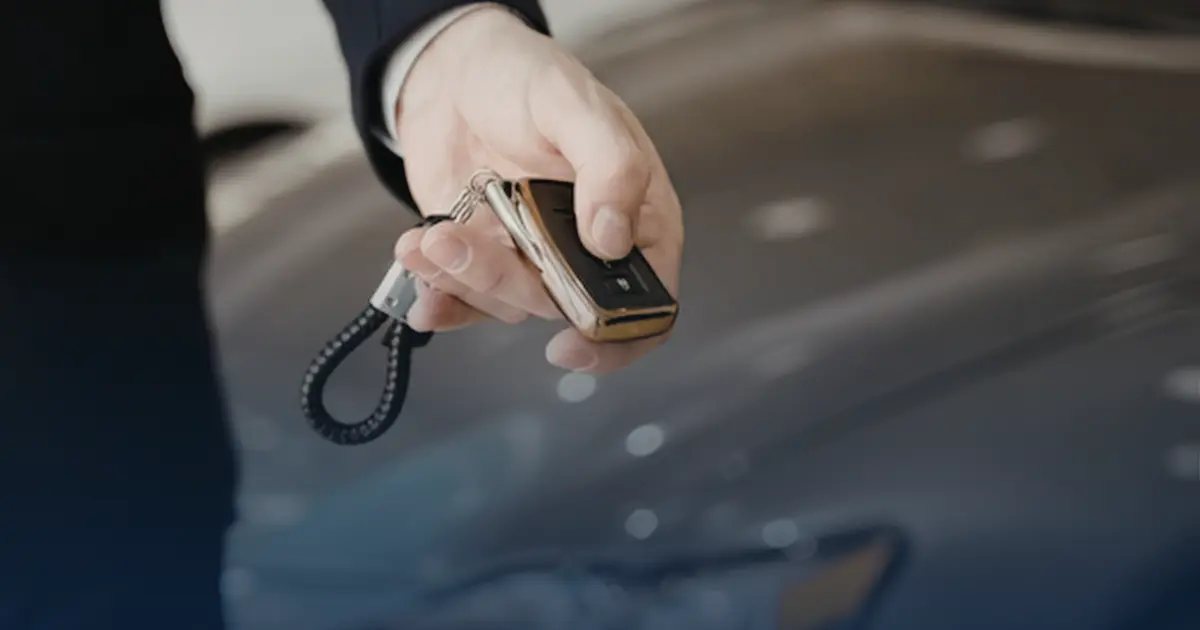 Persona sosteniendo las llaves de su auto junto a la puerta del vehículo